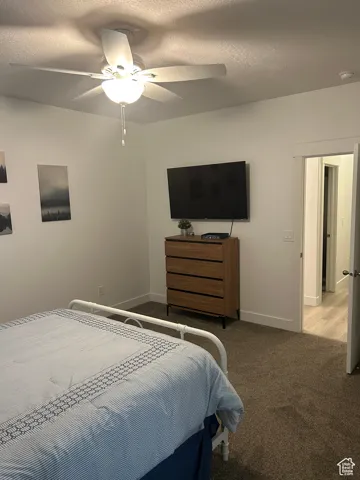 Bedroom featuring carpet floors, ceiling fan, and a textured ceiling