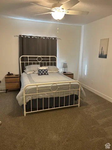 Carpeted bedroom featuring a textured ceiling and a ceiling fan