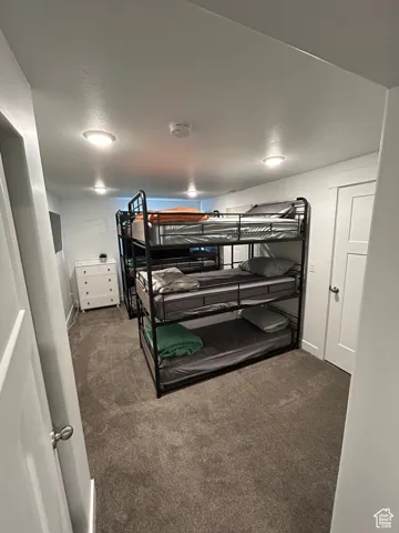 Bedroom with dark carpet and baseboards