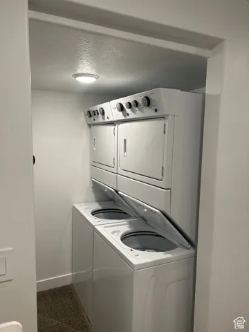 Laundry area featuring a textured ceiling and estacked washer and dryer