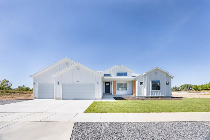 Modern farmhouse style home featuring board and batten siding, an attached garage, driveway, and a front yard