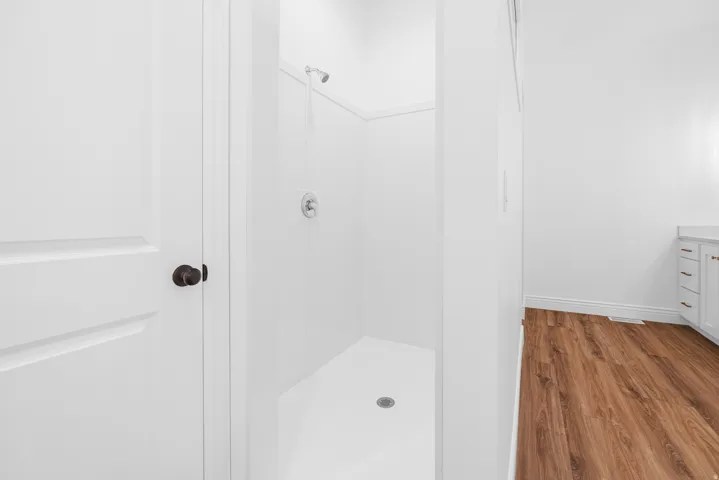 Full bathroom featuring wood finished floors, a stall shower, and vanity