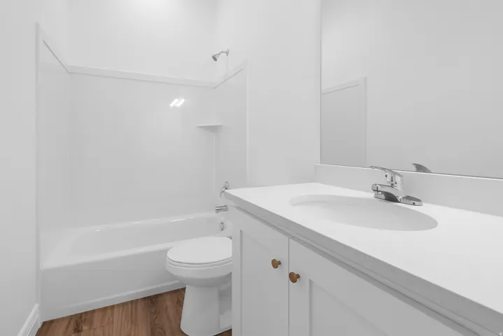 Bathroom featuring vanity, dark wood-style floors, and shower / bathtub combination