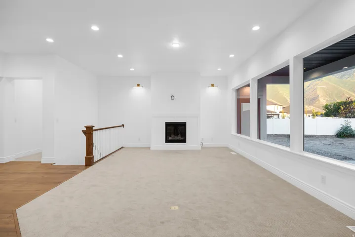 Unfurnished living room with a glass covered fireplace, recessed lighting, and light carpet