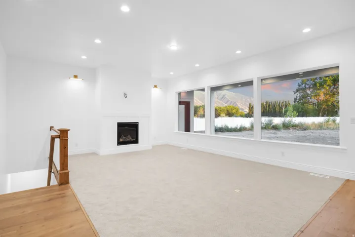Unfurnished living room with light colored carpet, a glass covered fireplace, and recessed lighting