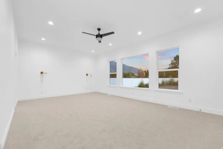 Empty room with ceiling fan, light colored carpet, and recessed lighting