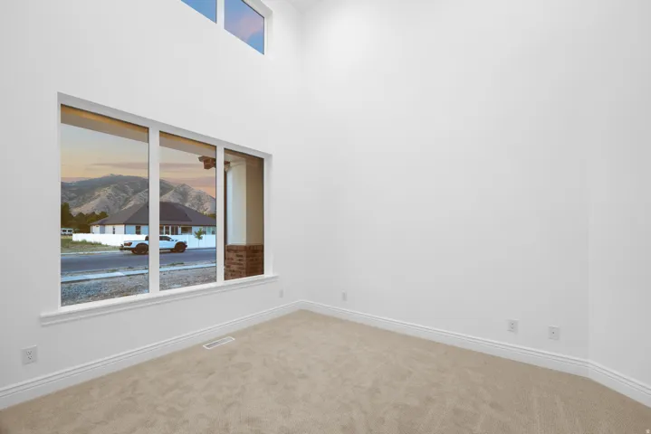 Empty room with carpet flooring, a mountain view, and a high ceiling