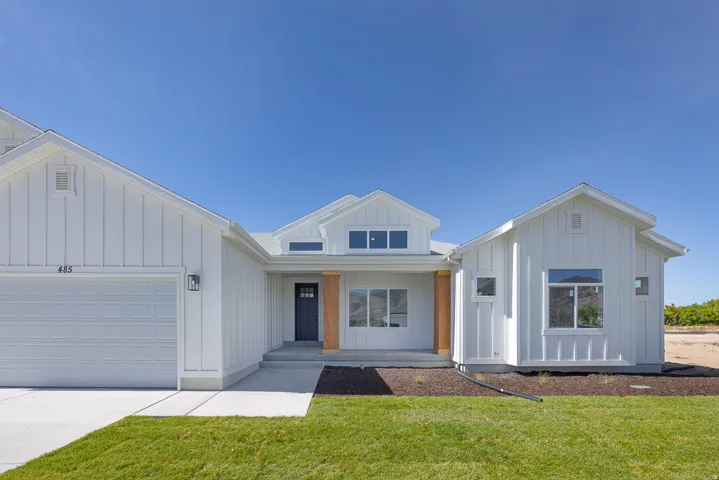Modern farmhouse with board and batten siding, a porch, an attached garage, a front lawn, and concrete driveway