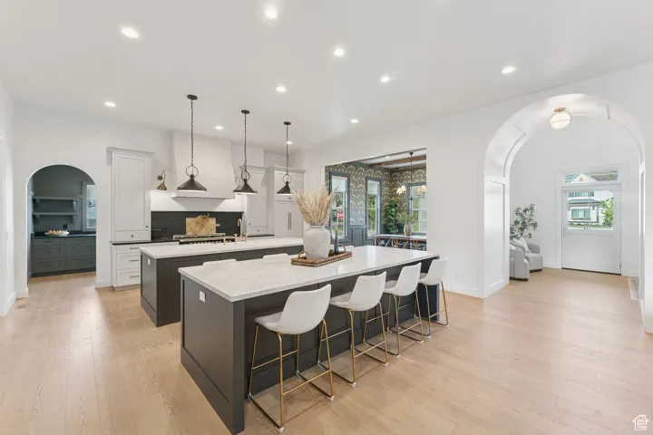 Kitchen featuring arched walkways, a breakfast bar, white cabinets, healthy amount of natural light, and recessed lighting