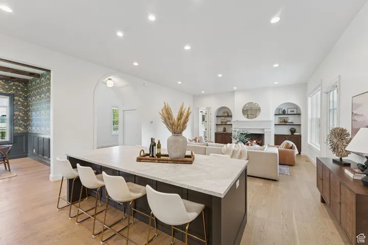 Kitchen with plenty of natural light, a lit fireplace, light wood-style floors, recessed lighting, and a center island