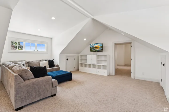 Living room with vaulted ceiling, light colored carpet, and recessed lighting