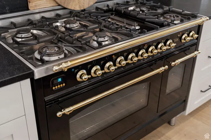 Detailed view of range with two ovens, white cabinets, and dark stone countertops