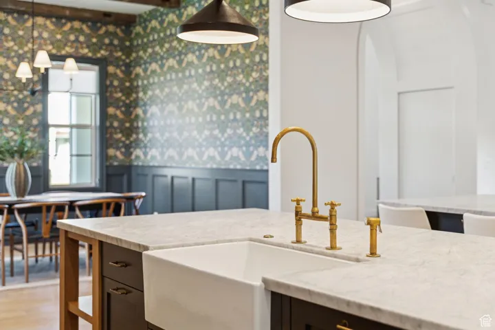 Kitchen featuring wainscoting, wallpapered walls, a decorative wall, light stone countertops, and light wood-style flooring