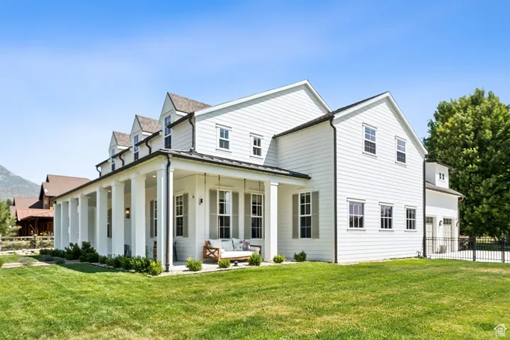 Rear view of property featuring a standing seam roof, an attached garage, a porch, a metal roof, and driveway