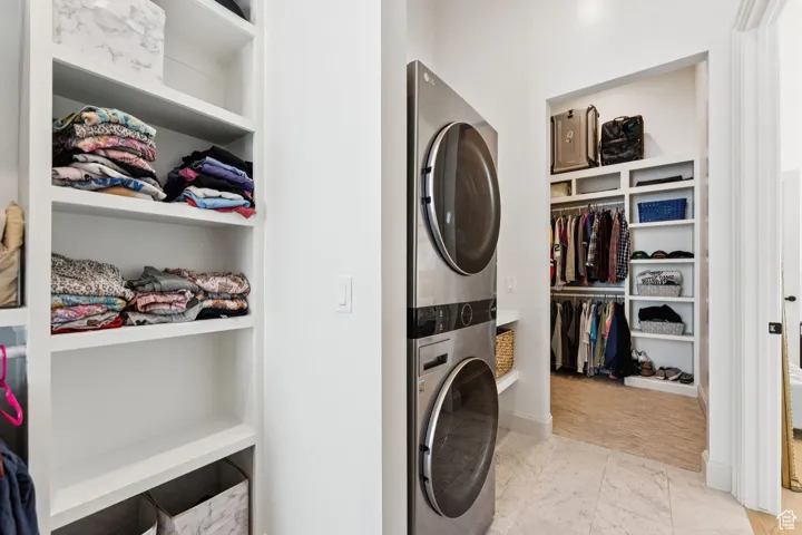 Laundry area featuring built in shelves and stacked washer and clothes dryer