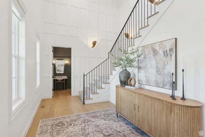 Foyer featuring stairway, light wood-style flooring, plenty of natural light, and a high ceiling
