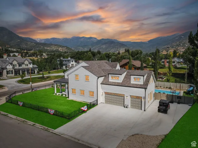 Modern farmhouse with concrete driveway, a mountain view, roof with shingles, and a garage