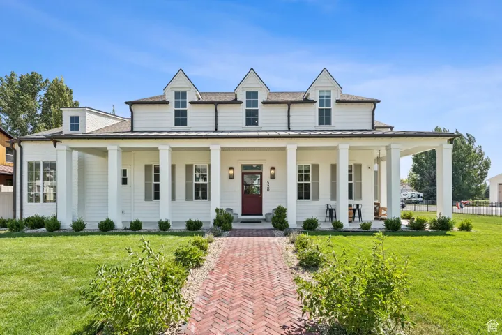 View of front of property featuring a porch, a standing seam roof, a shingled roof, and a metal roof