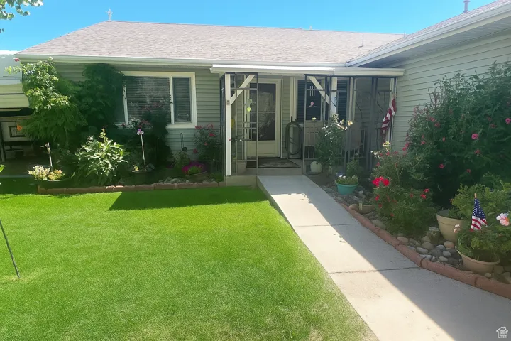 Property entrance featuring roof with shingles and a lawn
