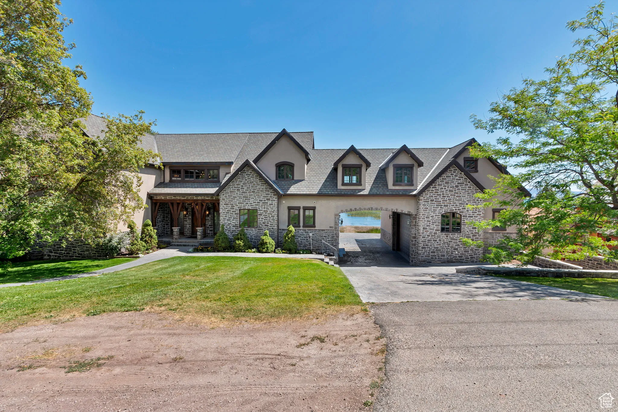 View of front of property featuring stone siding, driveway, and a front yard