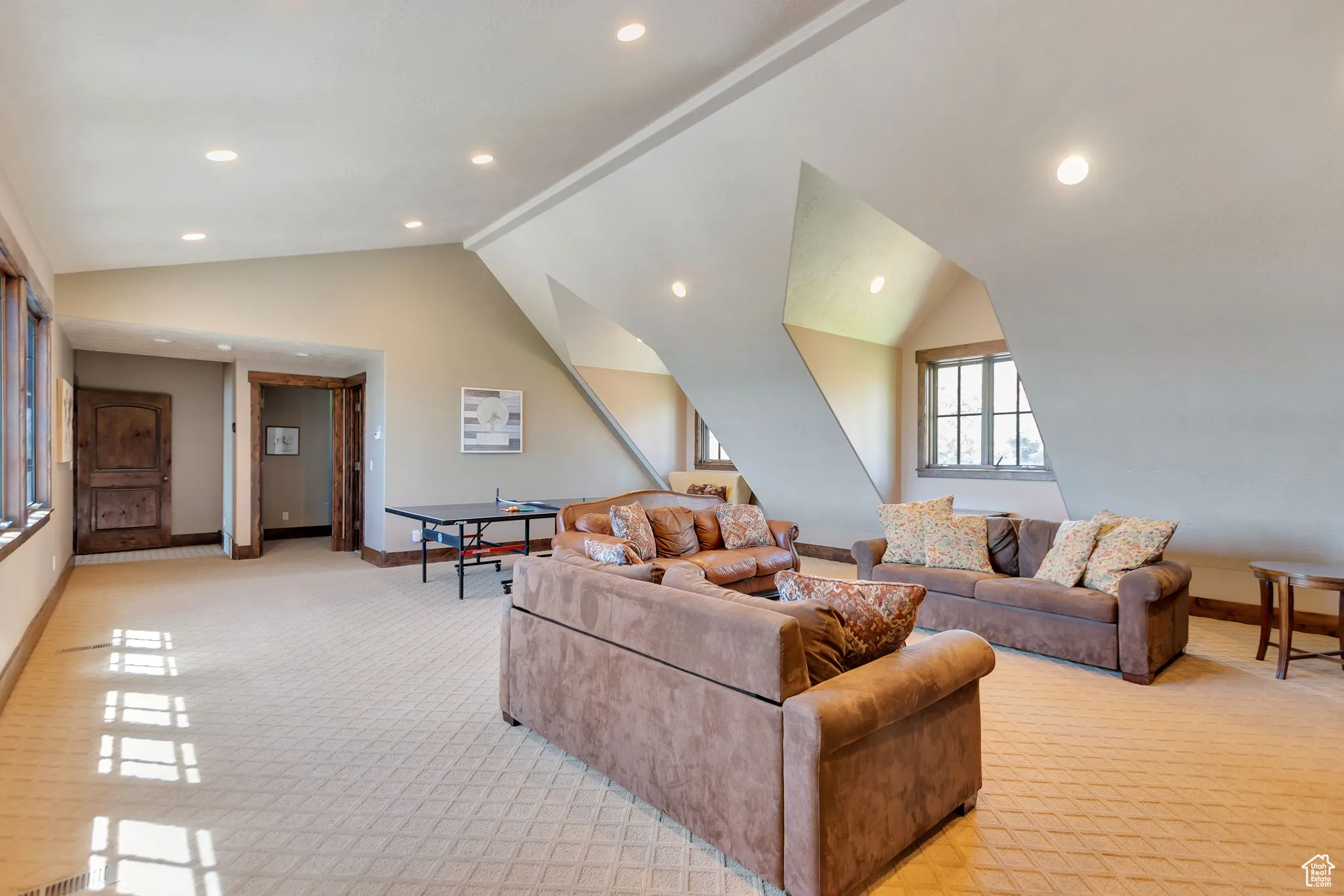 Living room with lofted ceiling, recessed lighting, and light colored carpet