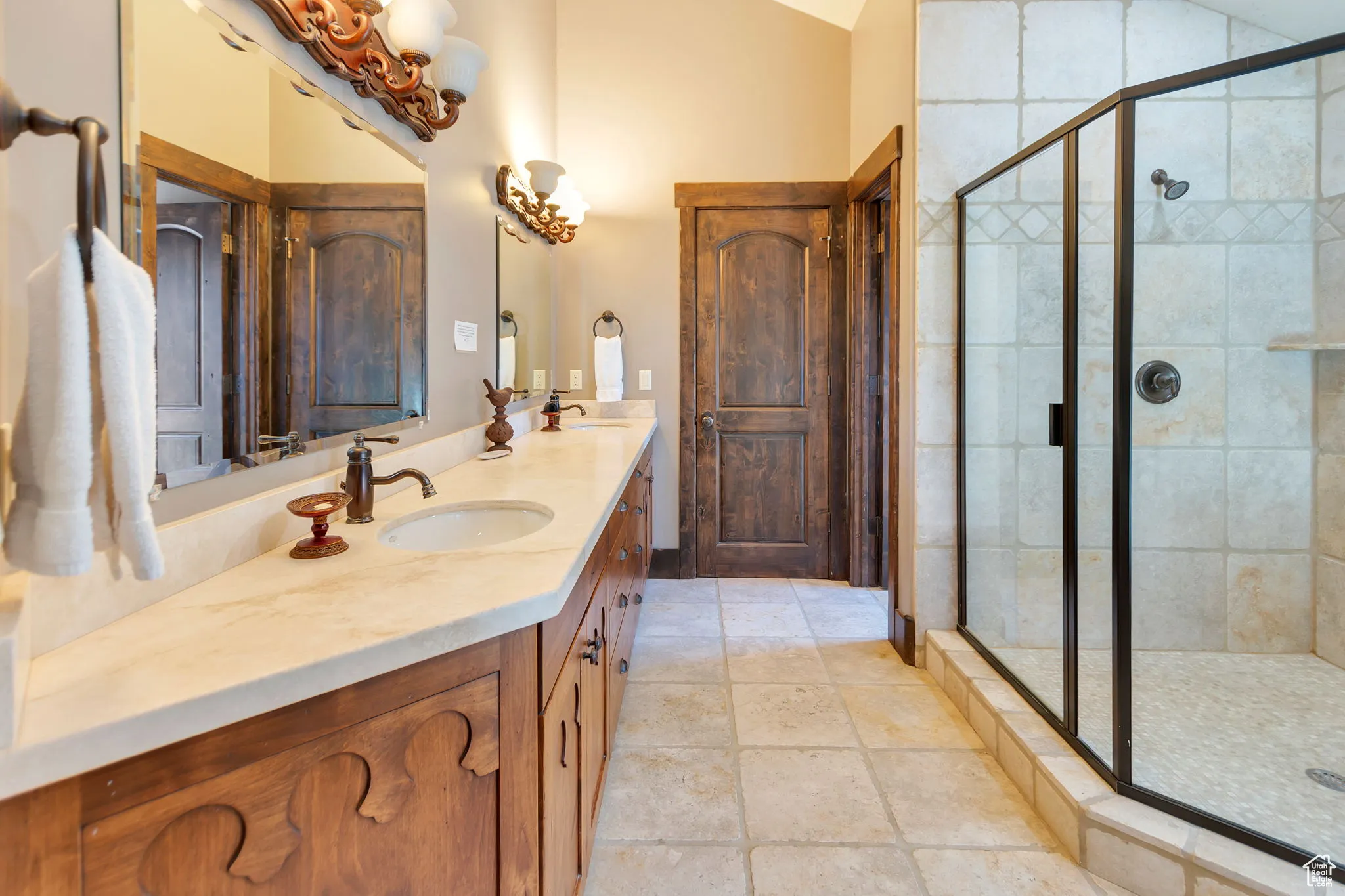 Full bath featuring double vanity, a stall shower, and lofted ceiling