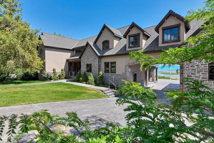 View of front of property featuring stucco siding, stone siding, and a front lawn