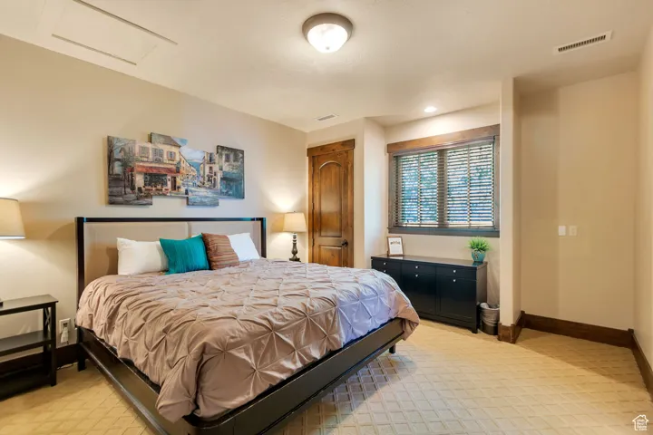 Bedroom featuring attic access, light colored carpet, and a closet