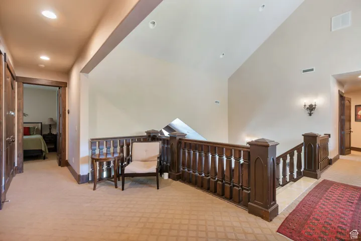 Hallway featuring an upstairs landing, high vaulted ceiling, light carpet, and recessed lighting