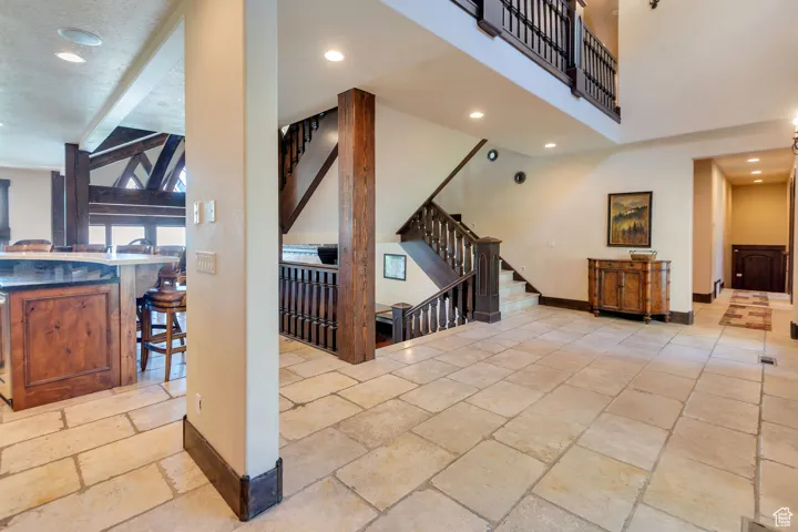 Living area with recessed lighting, stone tile flooring, stairway, and beam ceiling