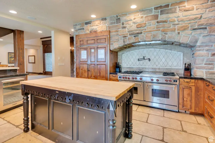 Kitchen featuring butcher block counters, range with two ovens, recessed lighting, tasteful backsplash, and wine cooler
