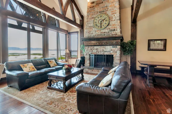 Living area with high vaulted ceiling, hardwood / wood-style floors, a fireplace, and a water view