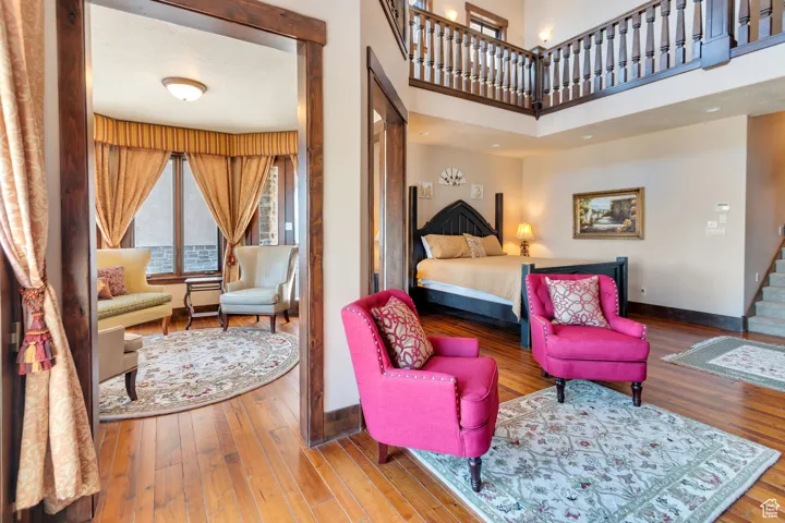 Primary Bedroom with hardwood / wood-style floors sitting room and a high ceiling