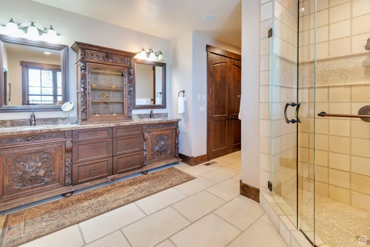 Primary Bathroom with double vanity, a stall shower, and light tile patterned floors