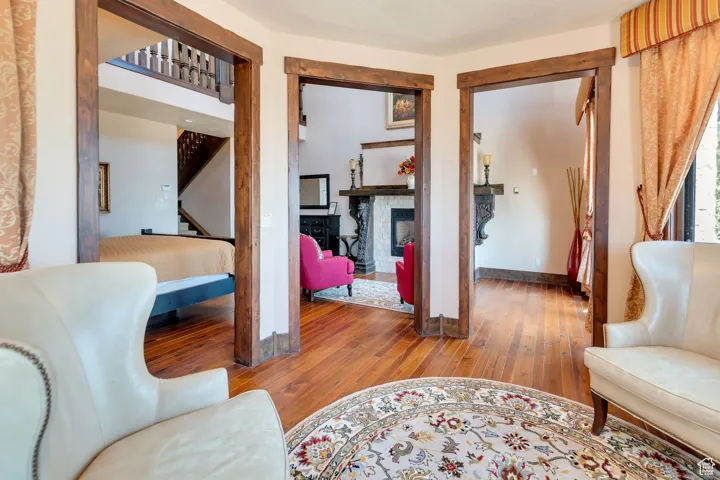 Primary bedroom sitting area with light wood-style floors, a fireplace, and stairs