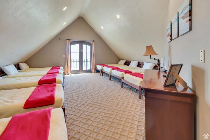 Bedroom featuring a textured ceiling, french doors, light carpet, access to exterior, and vaulted ceiling
