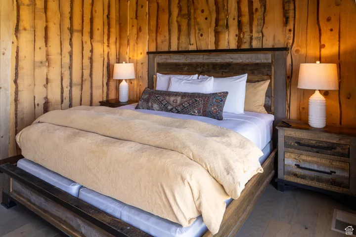 Bedroom with wood walls and dark wood-style flooring
