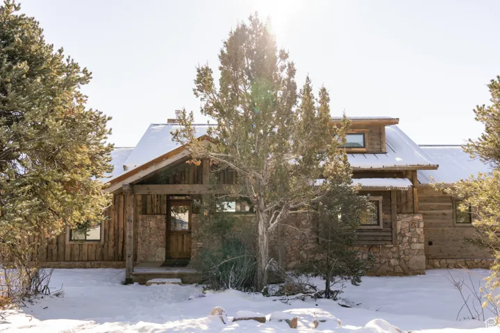 View of front of property with a chimney and stone siding