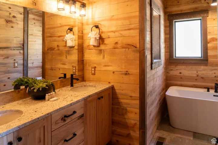 Bathroom with wood walls, double vanity, and a freestanding tub
