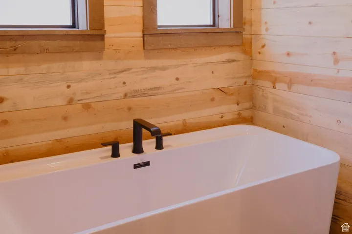 Full bathroom with a freestanding bath and wood walls