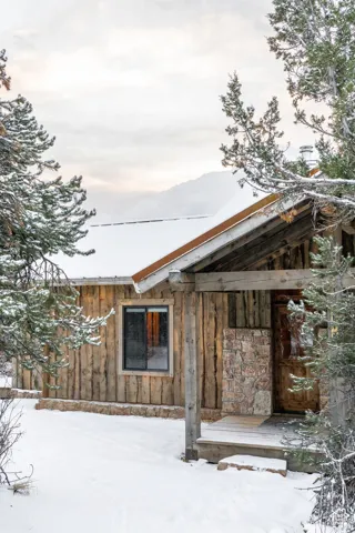 View of snowy exterior featuring board and batten siding and stone siding