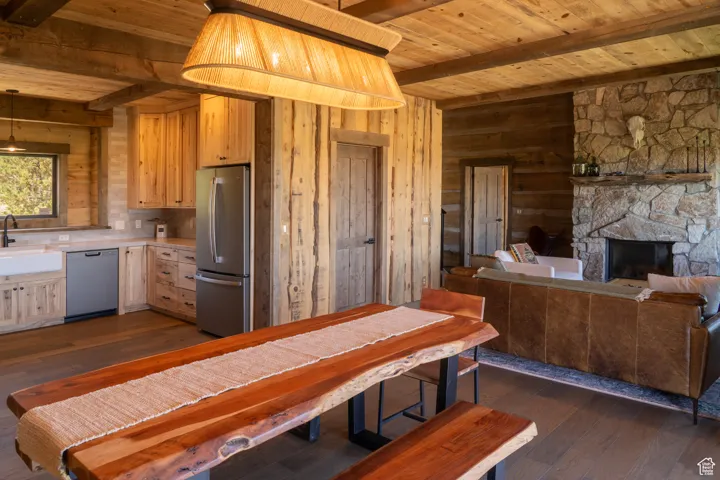 Kitchen featuring dark wood finished floors, light countertops, appliances with stainless steel finishes, a fireplace, and a wood ceiling with exposed beams