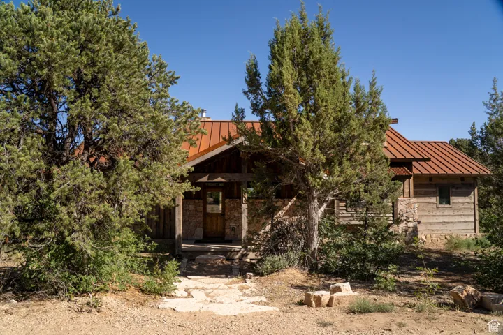 View of property hidden behind natural elements with a standing seam roof, a metal roof, and stone siding