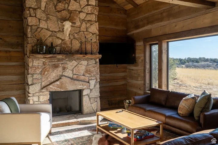 Living area featuring a fireplace, a wood ceiling with exposed beams, wooden walls, and high vaulted ceiling