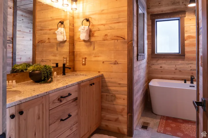 Bathroom featuring wood walls, a freestanding tub, and double vanity