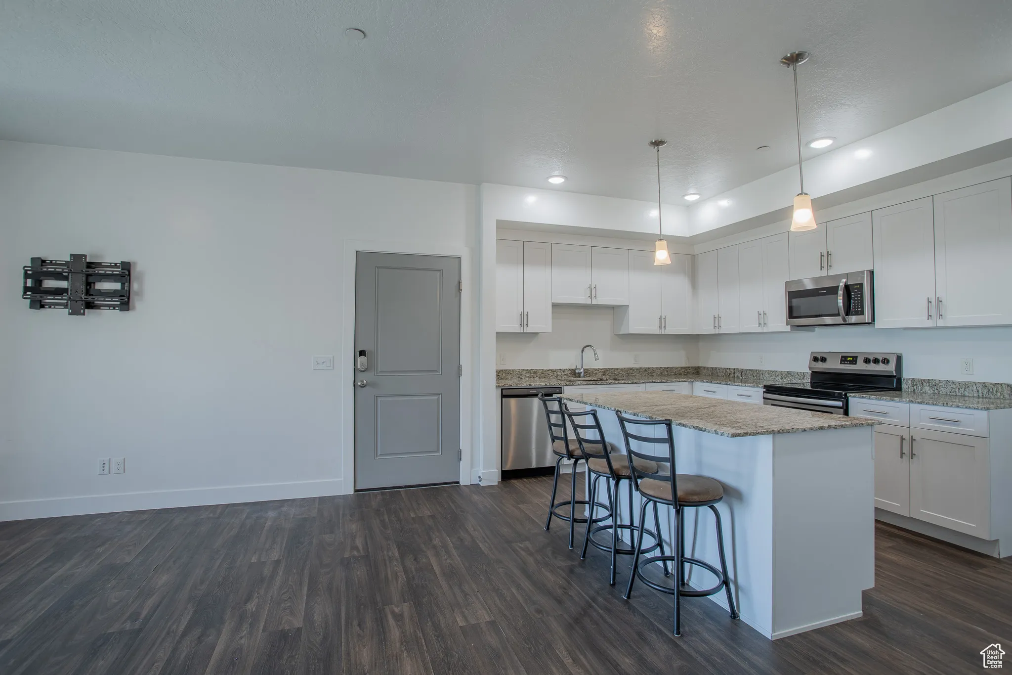Kitchen with recessed lighting, white cabinetry, a kitchen breakfast bar, decorative light fixtures, and dark wood finished floors