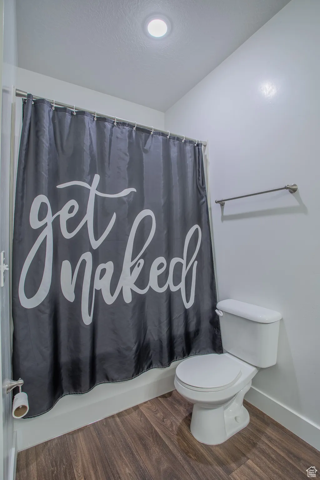 Bathroom with dark wood-style floors, shower / tub combo with curtain, and a textured ceiling