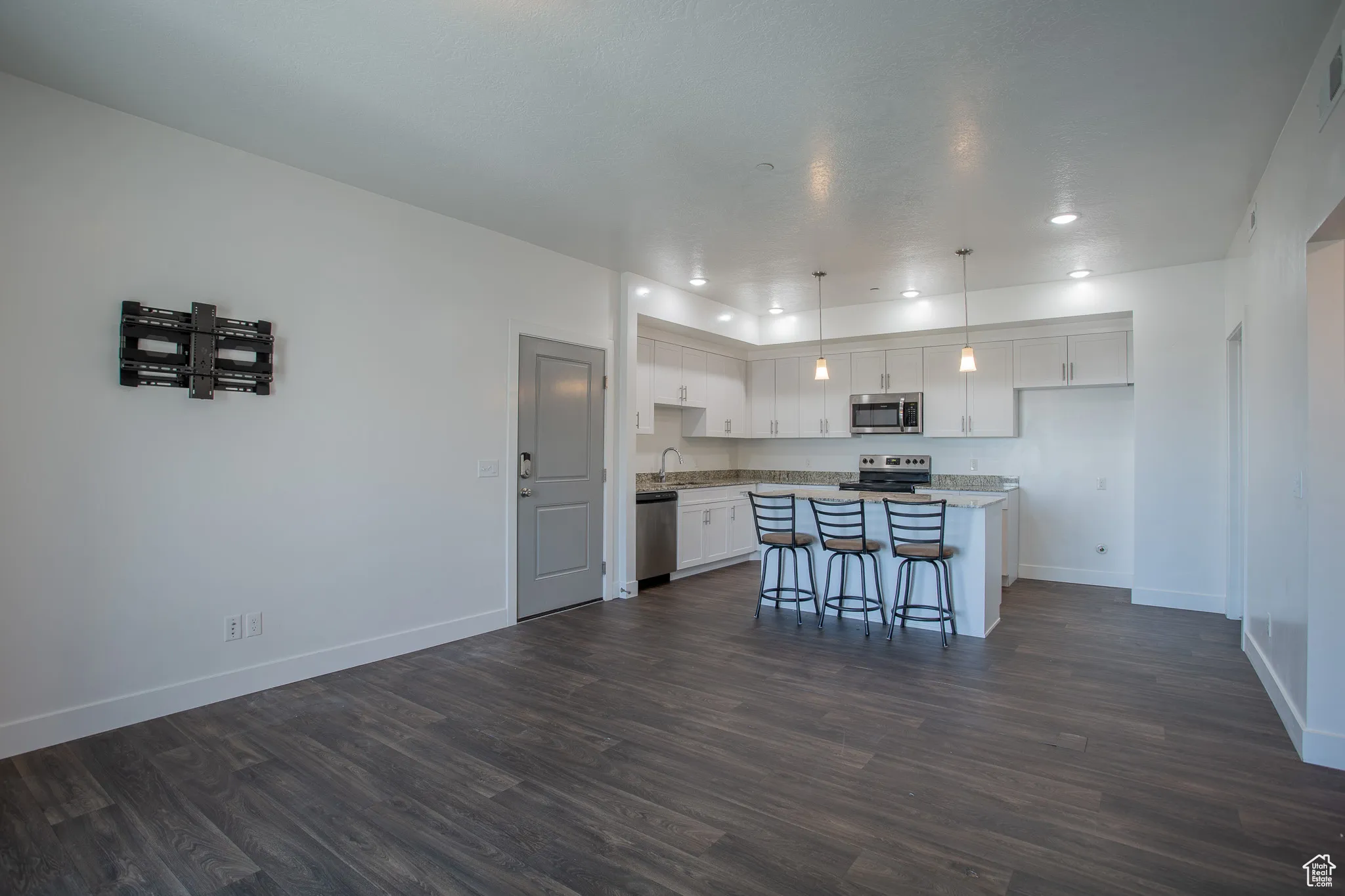 Kitchen with white cabinets, dark wood-style floors, hanging light fixtures, a breakfast bar area, and recessed lighting