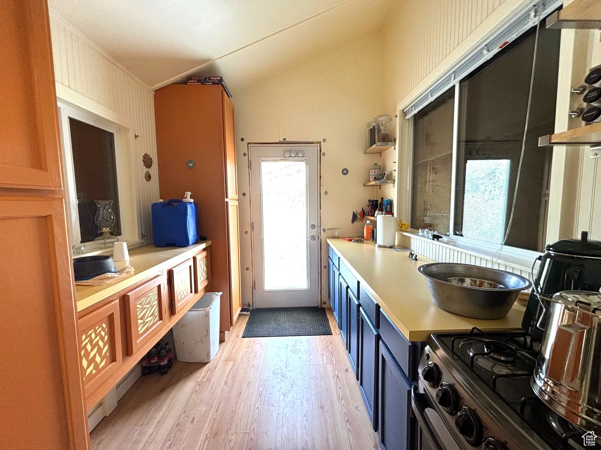 Kitchen featuring open shelves, light countertops, blue cabinetry, stainless steel gas range, and light wood-type flooring