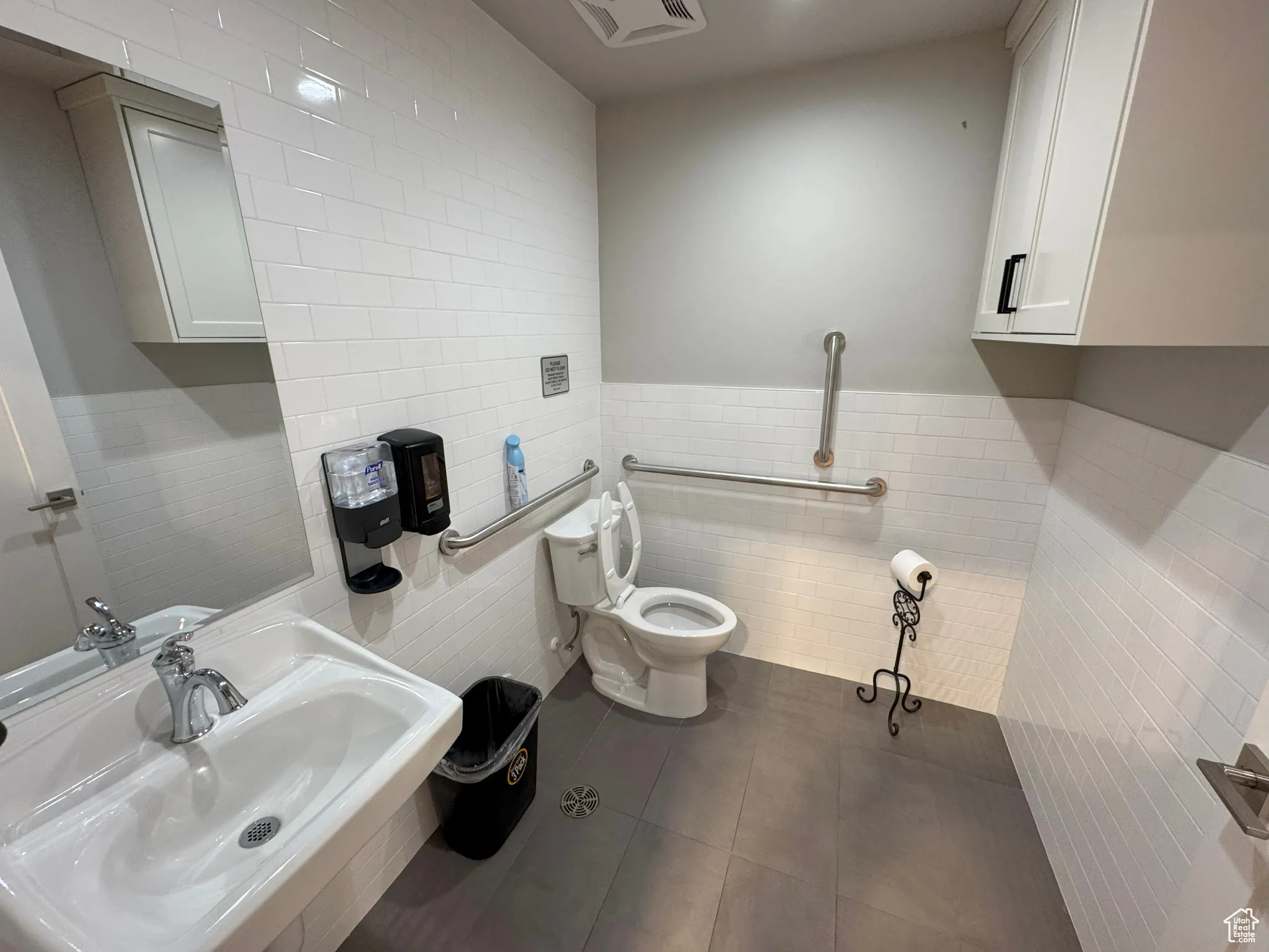 Half bathroom with tile walls, tile patterned flooring, and wainscoting